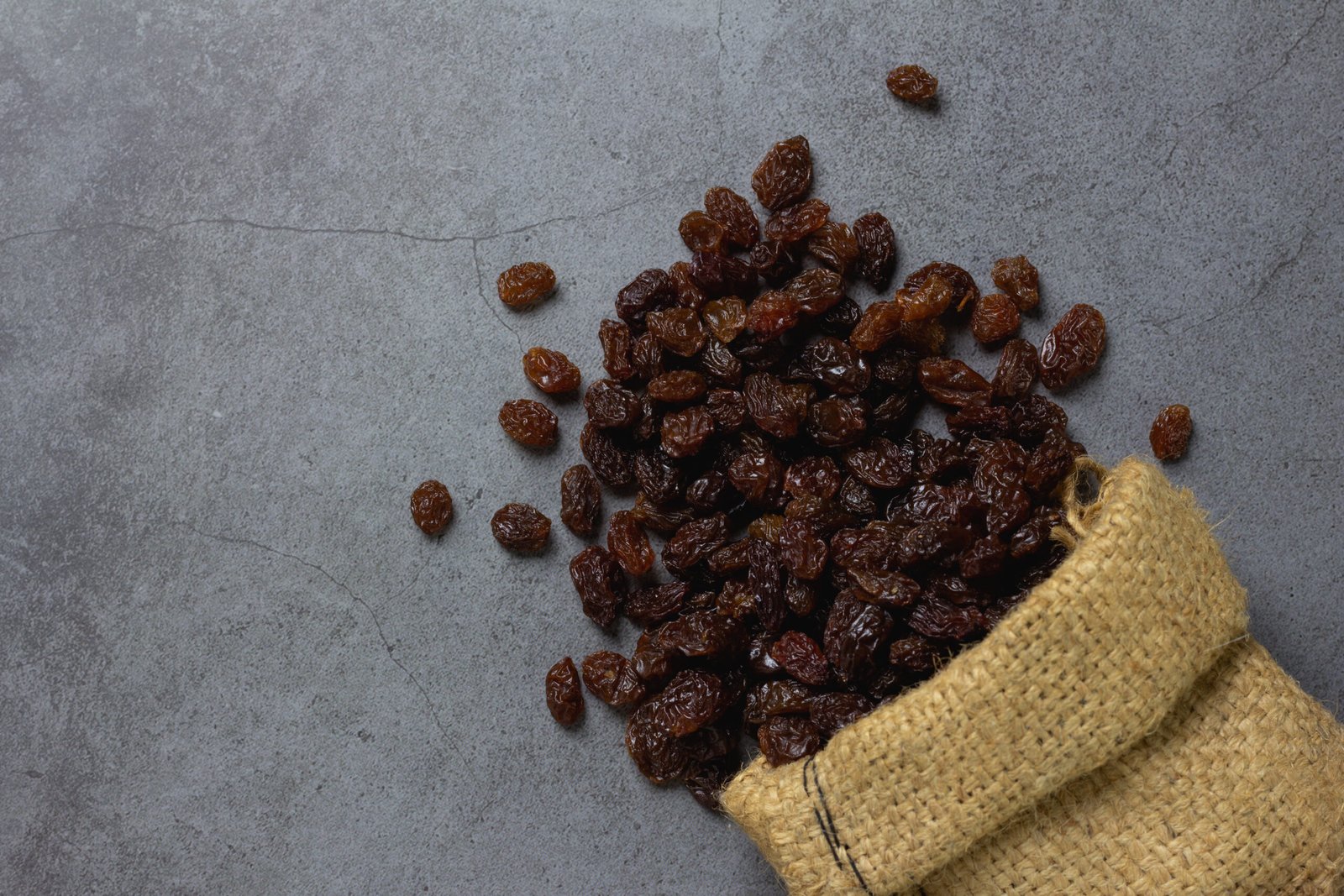 ''benefits of black raisins'' Dried raisins in burlap bagl on table